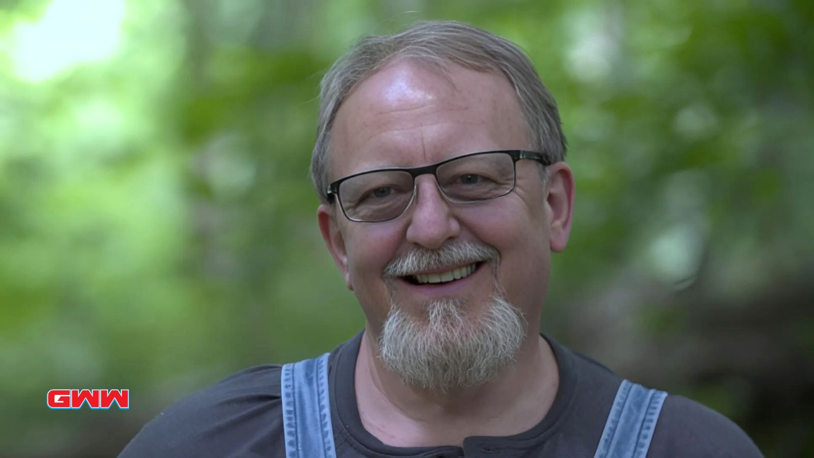 Eric "Digger" Manes smiling outdoors, wearing glasses and casual clothing.