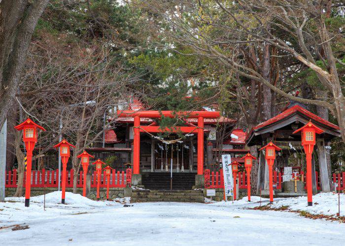 A torii gate dusted with snow during winter in Kyoto.