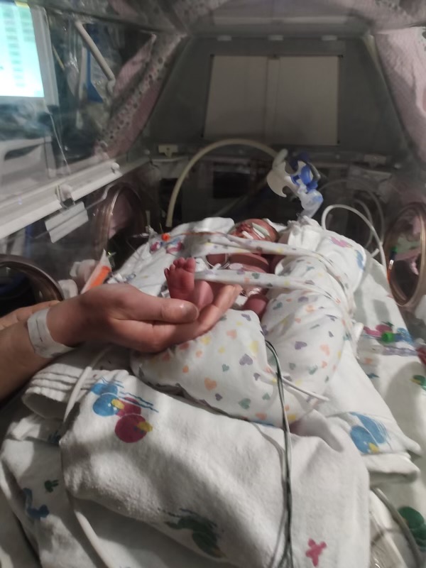 Mom holds her baby's foot in the NICU.