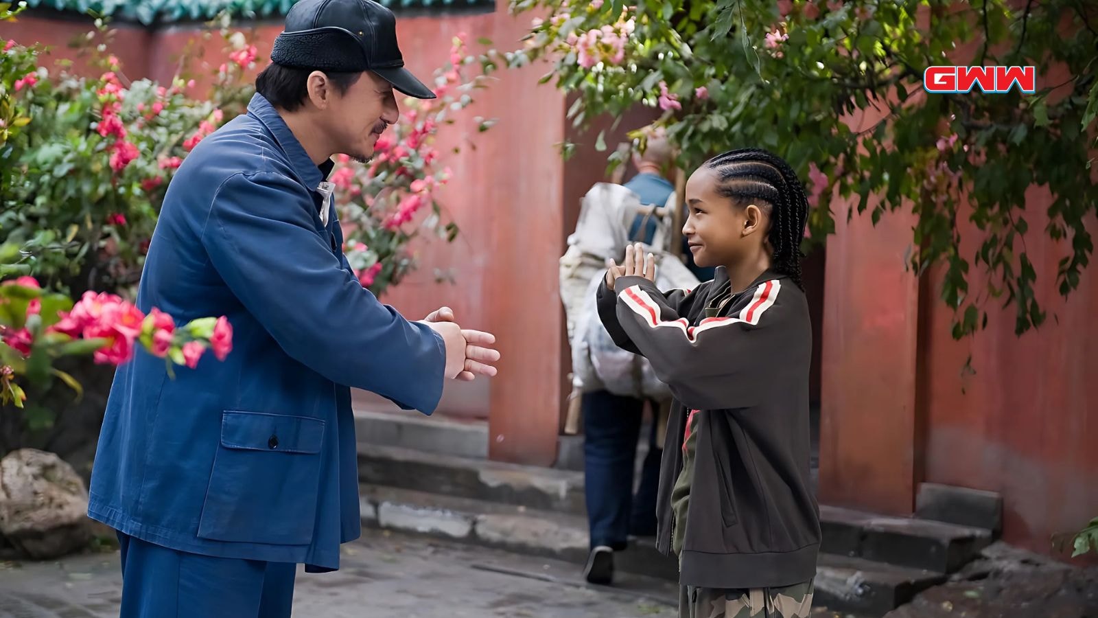 Jackie Chan greeting Jaden Smith respectfully in a training courtyard.