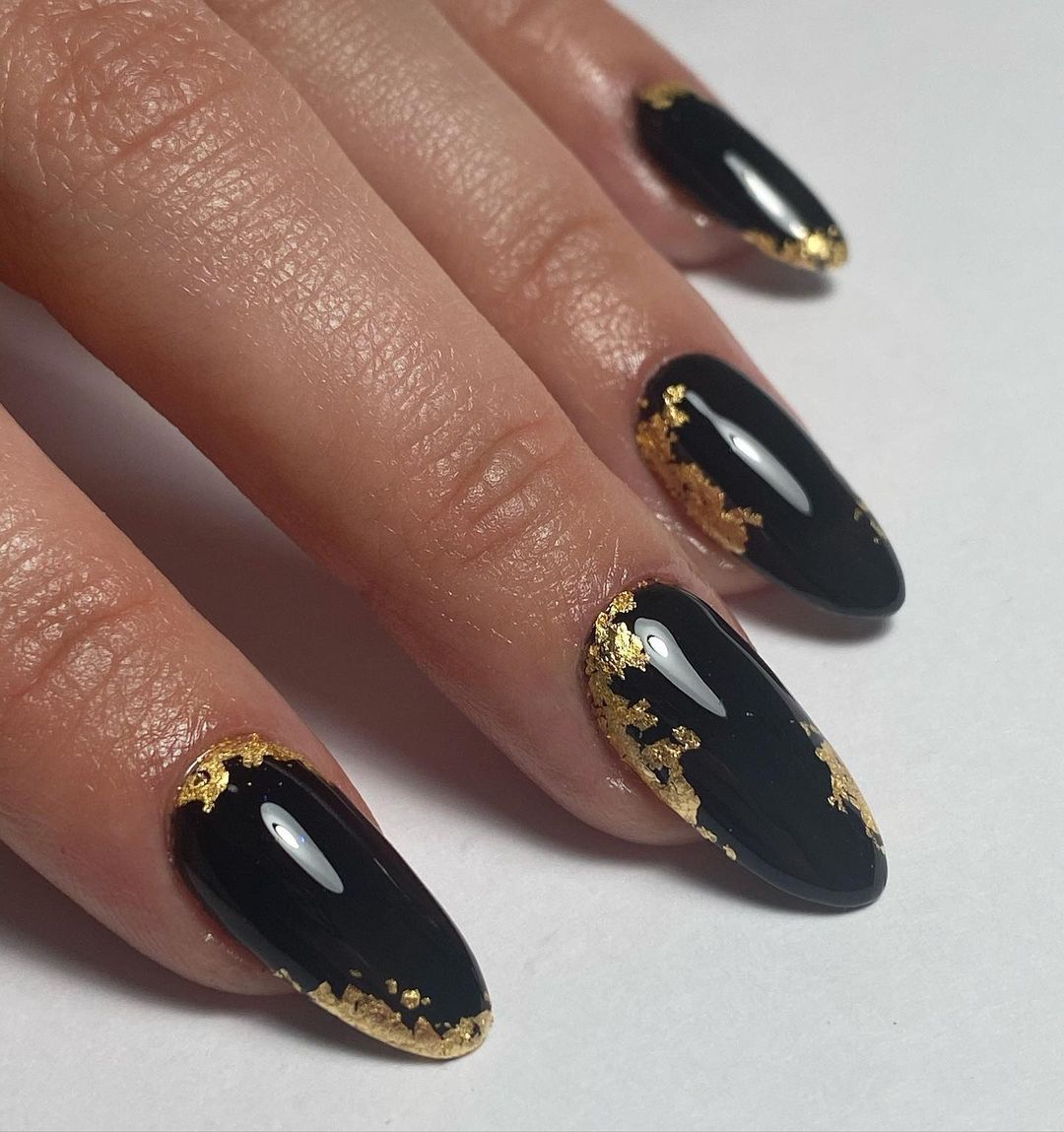 Close-up of a person's hands with black nails having Gold Leaf Details