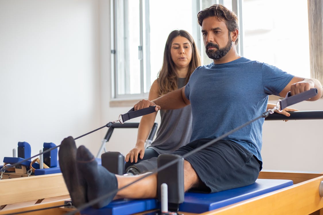 Free Man with prosthetic leg working out with trainer in gym, showcasing strength and rehabilitation. Stock Photo