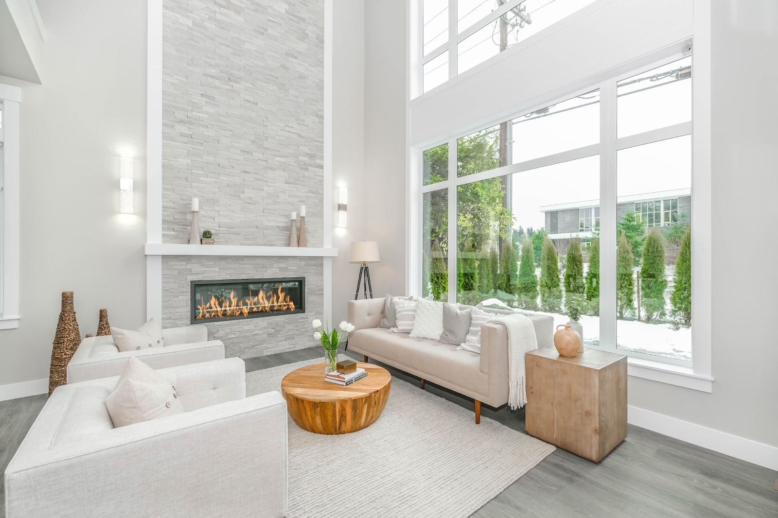  This image depicts a living room with large windows looking out to a snowy backyard. 