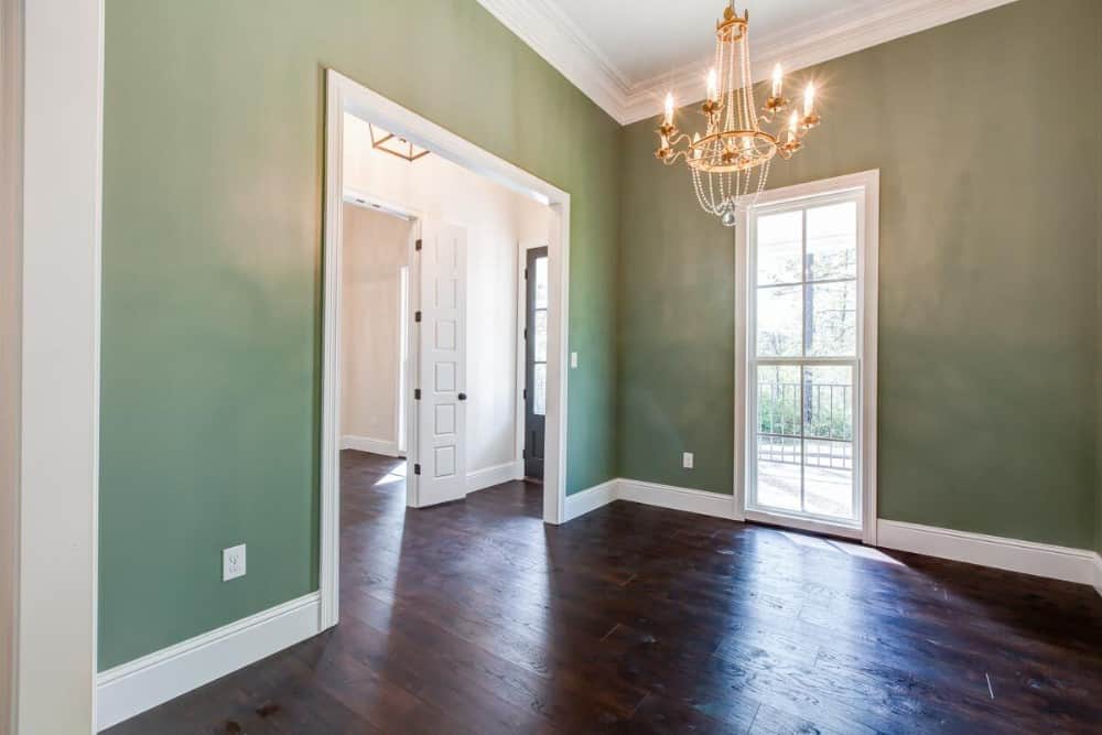 Flex room with sage green walls, a tall window, and a beaded chandelier.