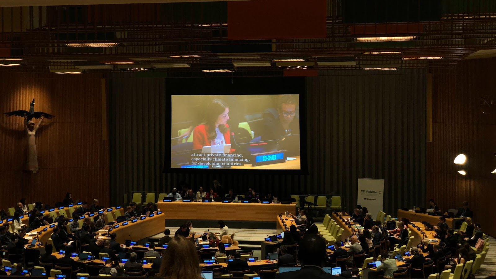 A large screen showing a group of people in a conference room

Description automatically generated