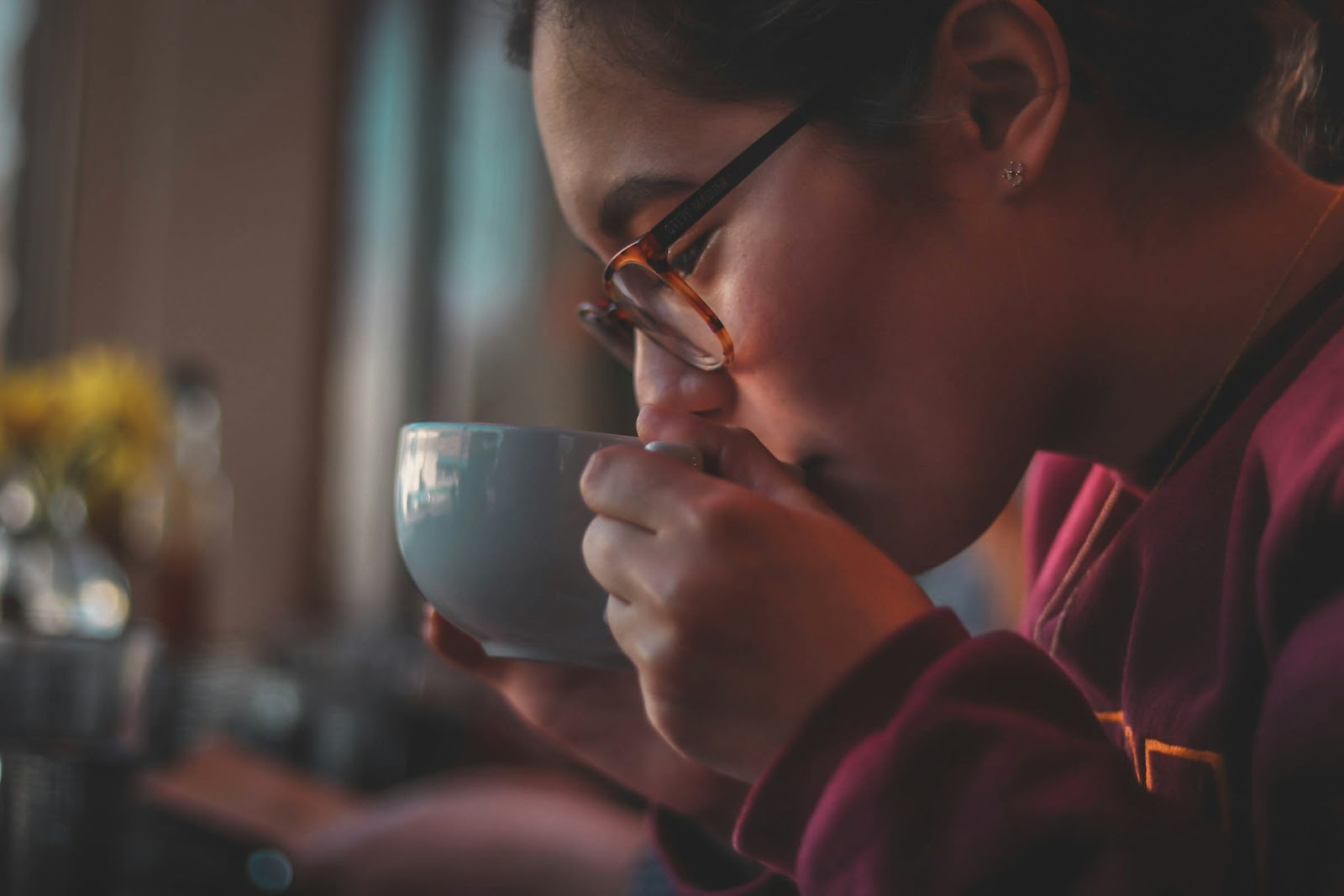 A woman sips tea from her cup gently in the evening