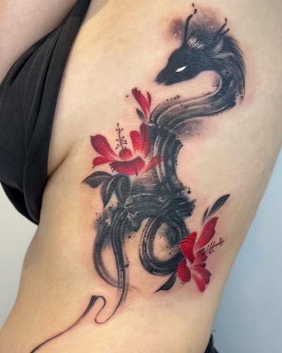 A small musical note tattoo covered strategically with dragon and florals