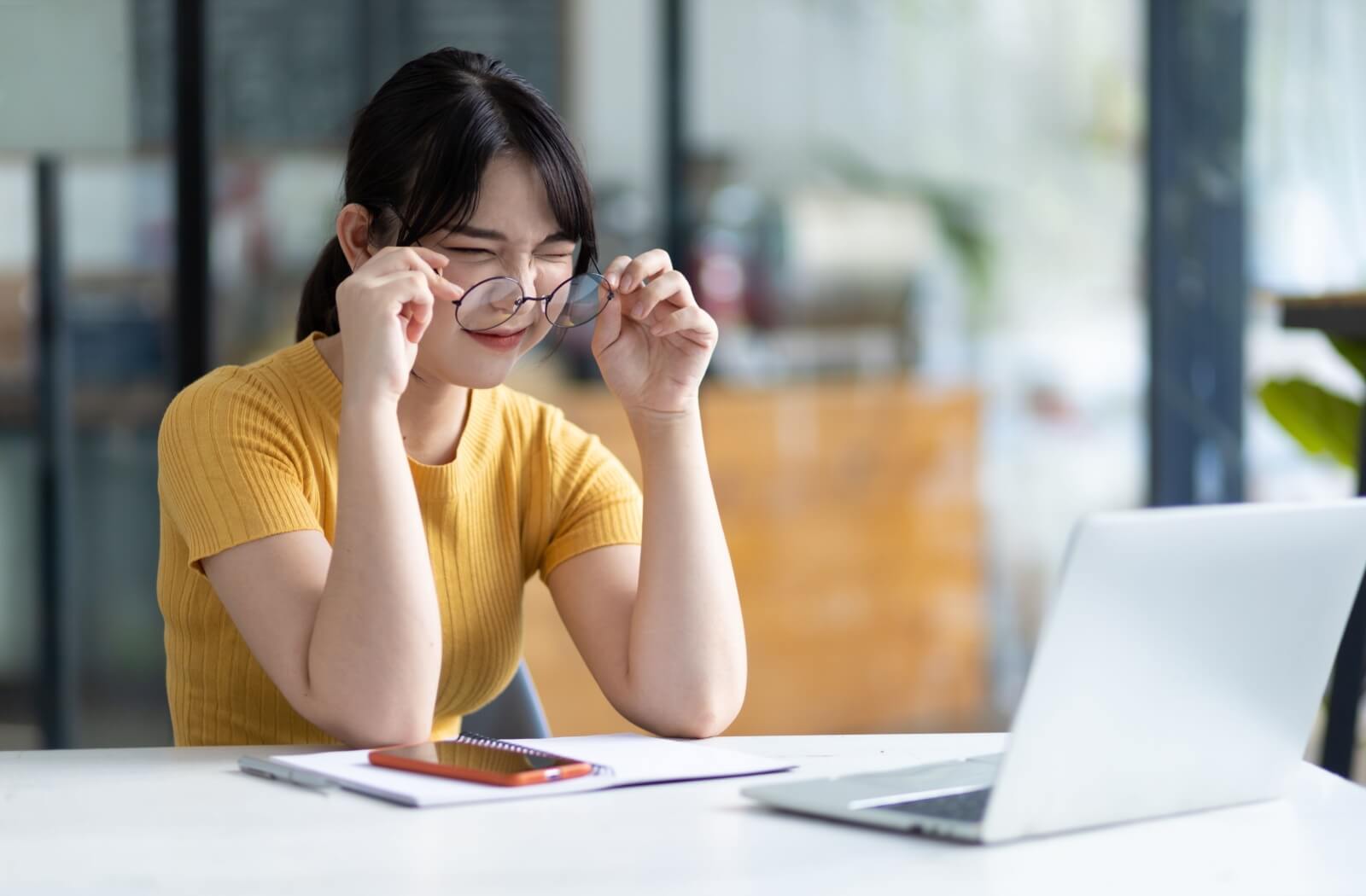 A person struggles to see their laptop due to a refractive error.