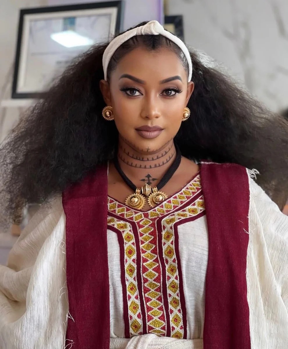 Woman in modern embroidered white Habesha dress with red and yellow embroidery