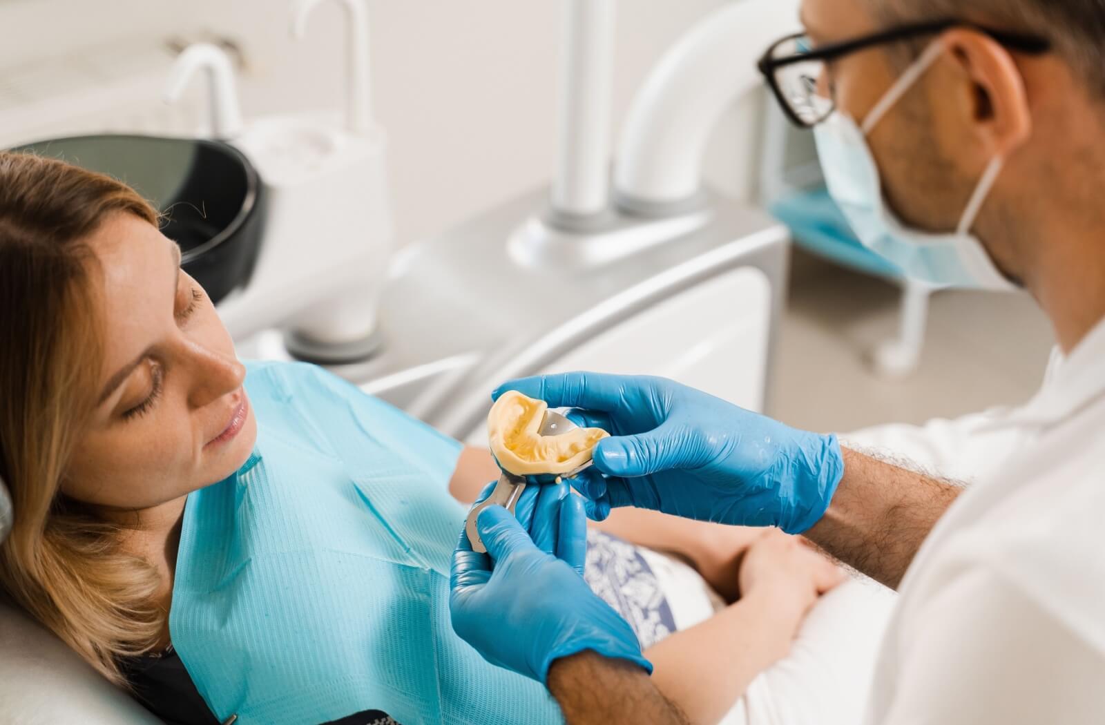 A dentist holds a tray carrying a patient's dental impression.