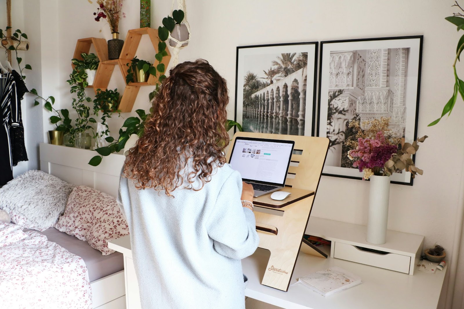 Woman working while standing next to her bed