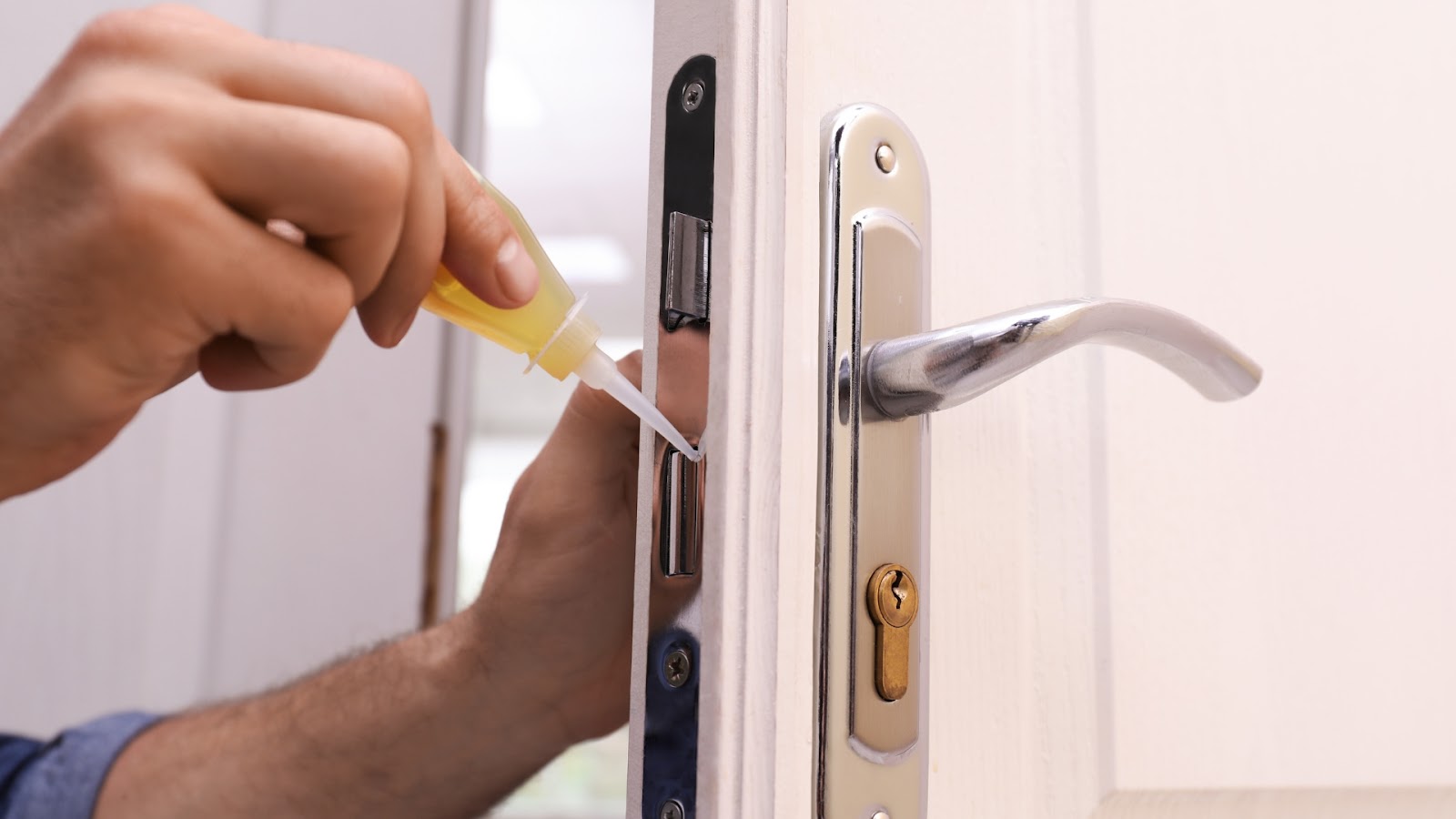 Applying lubricant to the door lock latch as part of maintenance.