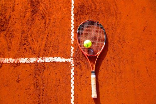 Free Tennis Ball on Tennis Racket on Floor Stock Photo