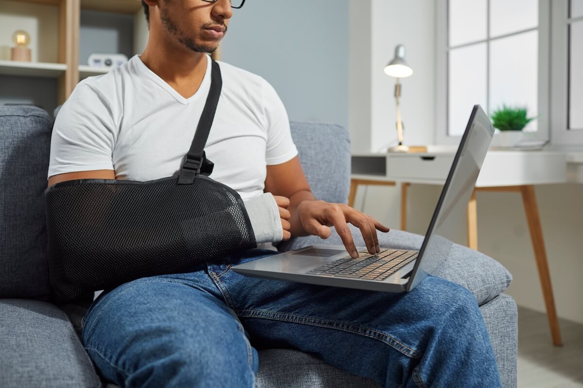 Medical leave of absence: injured man using a laptop