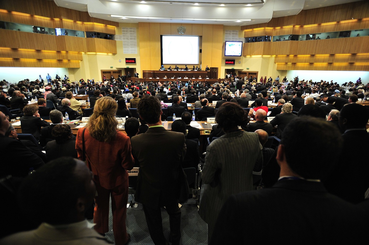 A large conference room filled with attendees facing a stage where a panel of speakers is presenting.