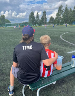 A person and child sitting on a bench on a football field Description automatically generated