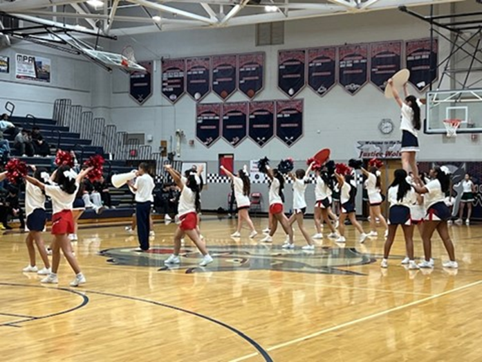 Justice High School Winter Wolves cheerleading team leading a cheer in the gym.