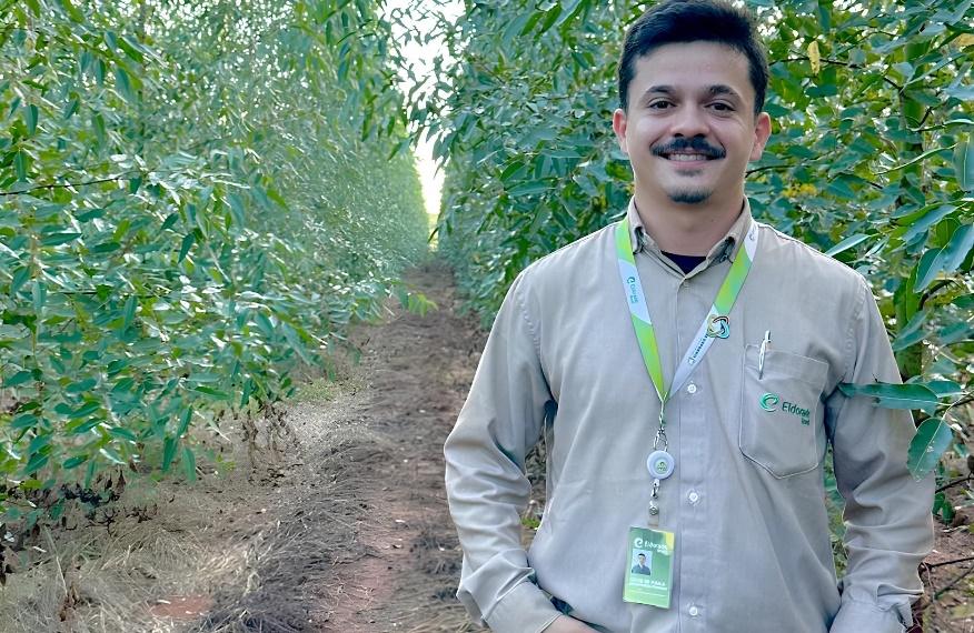 Pessoa posando para foto em local com vegetaoDescrio gerada automaticamente