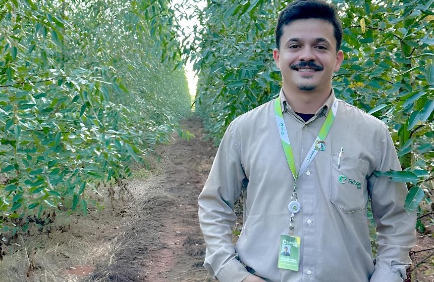 Pessoa posando para foto em local com vegetaçãoDescrição gerada automaticamente