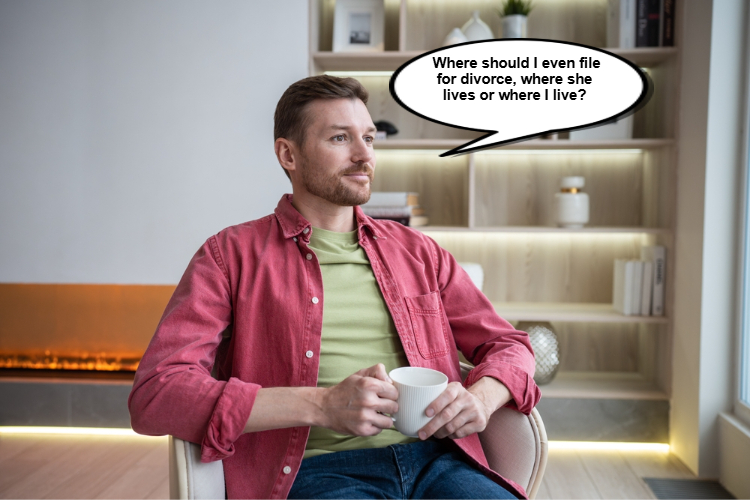 A man in a red shirt sits in a chair holding a mug. A speech bubble reads, "Where should I even file for divorce, where she lives or where I live?.