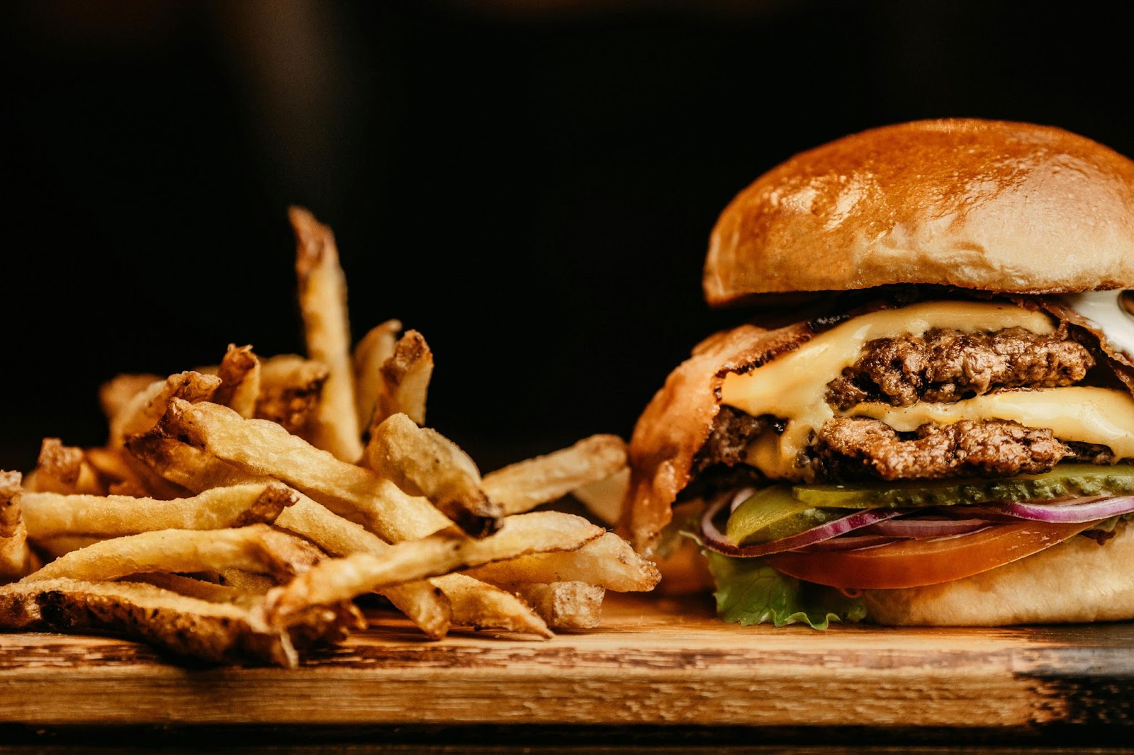 A picture of a burger and fries on a wooden board.