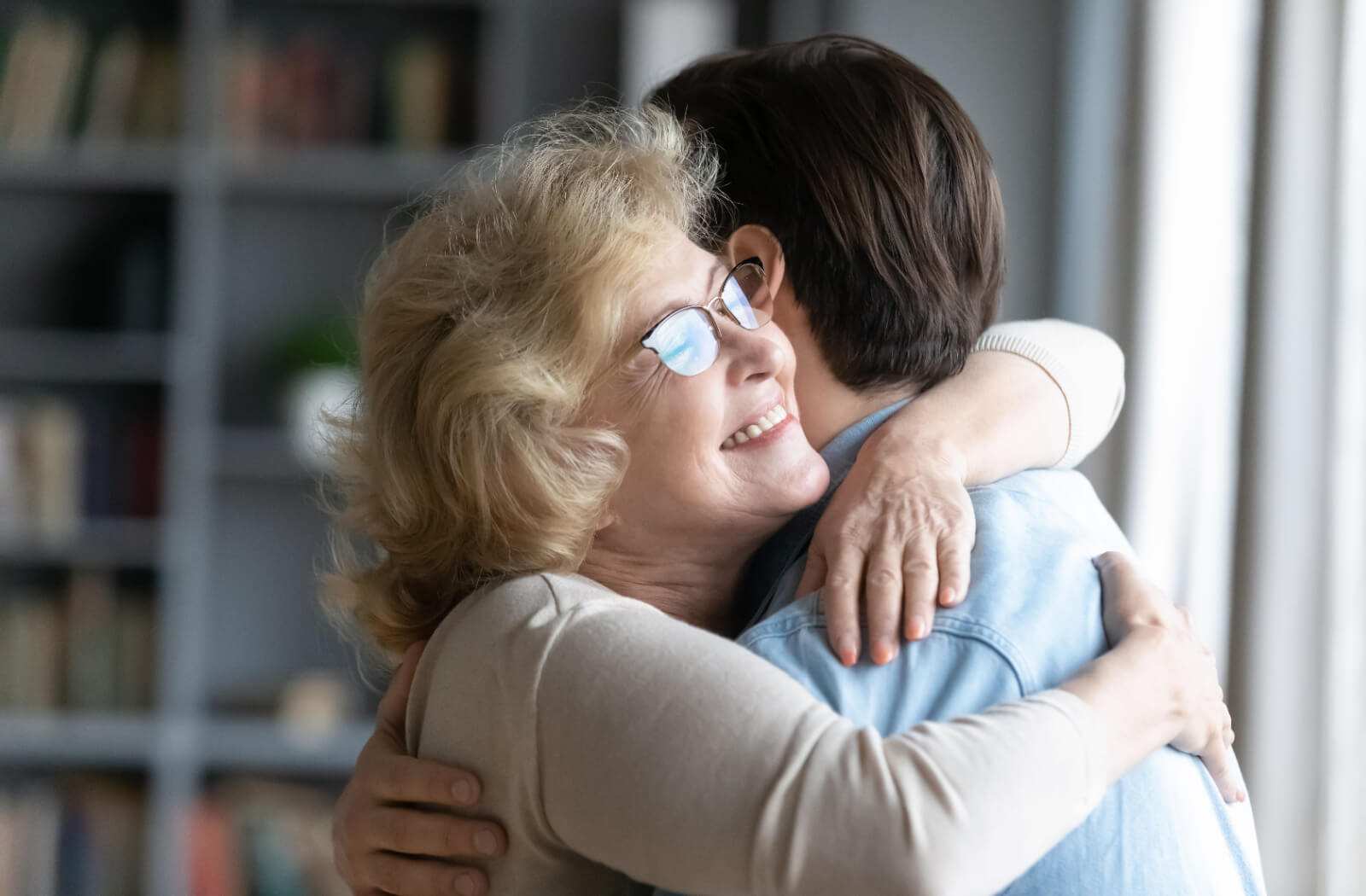 An older adult happily hugging their adult child after a move to senior living.