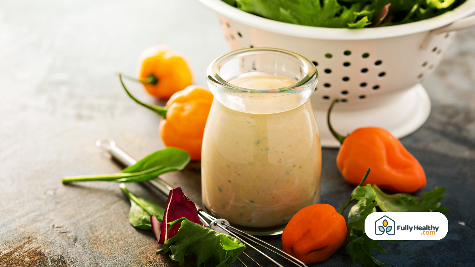 Jar of dressing with greens and peppers beside a colander
