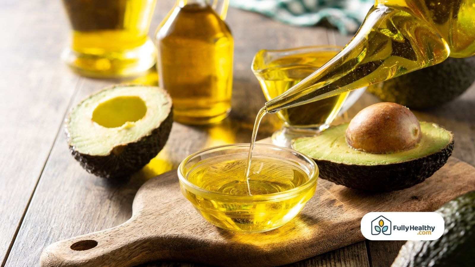 Pouring avocado oil into glass bowl with fresh avocados nearby