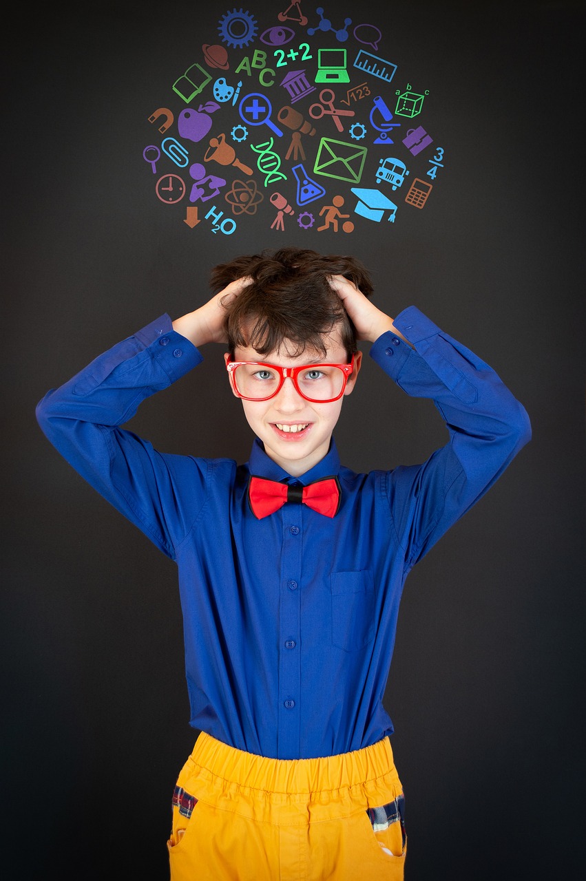 Young boy stands in front of a black board with scientific images in the background. 