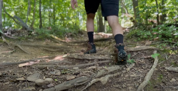 Merrell Moab 3 hiking boots on a uneven trail, showcasing their durability and design.