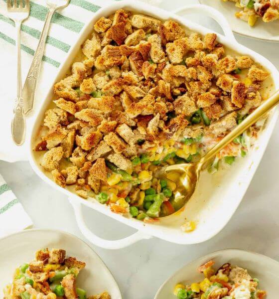 Vegetable casserole in white baking dish with serving spoon