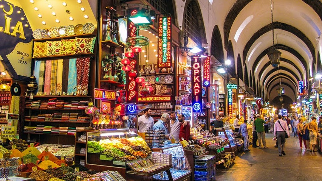 Vibrant stalls inside the Egyptian Bazaar (Spice Bazaar) in Istanbul, Turkey, featuring colorful spices, sweets, textiles, and glowing lanterns under arched ceilings, bustling with shoppers