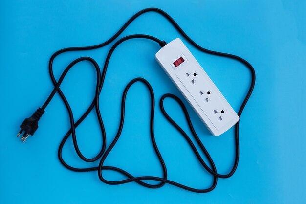 Electrical power strip and plug on blue wall. Top view