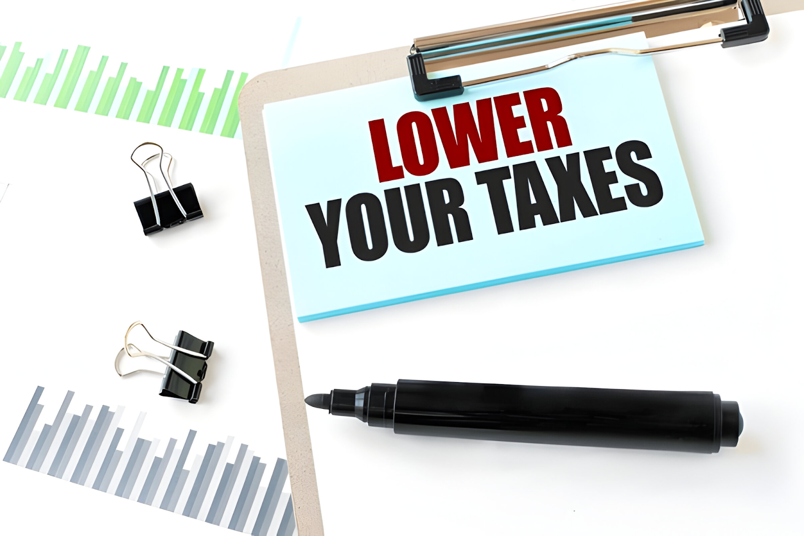 Clipboard with a note stating 'Lower Your Taxes' alongside charts and a marker, illustrating how accountants handle international tax issues to reduce tax liabilities.