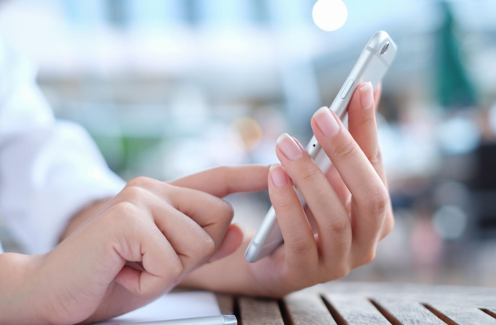 Close-up of person's hands as they set a reminder on their smartphone to pay their loan on time.