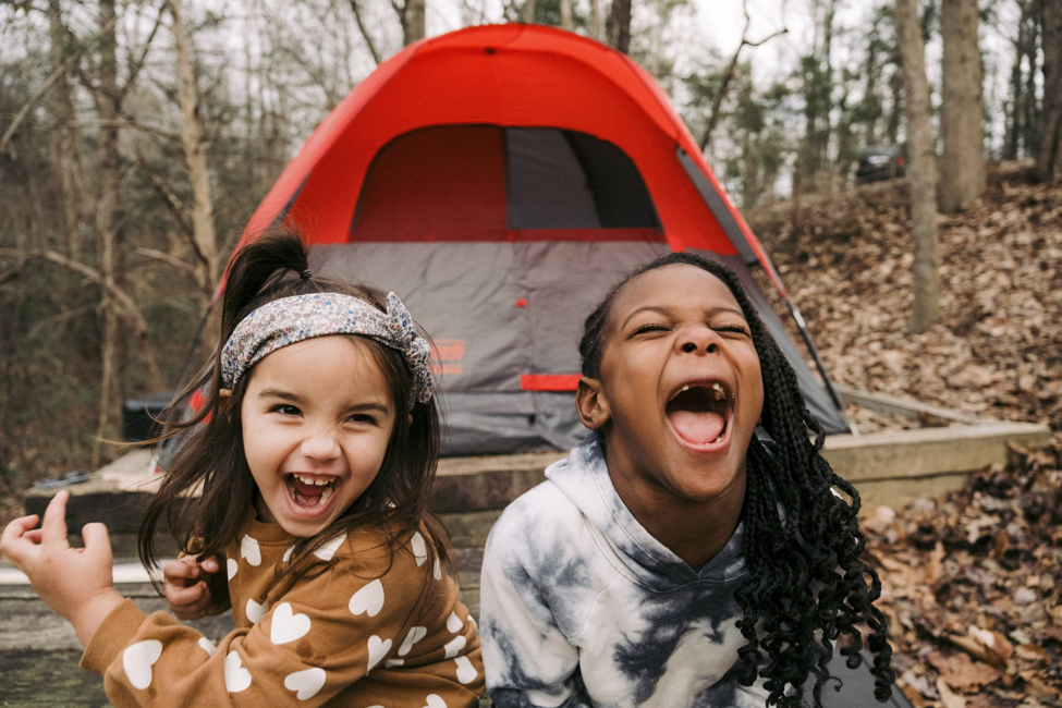 Two playful girls next to a tent 