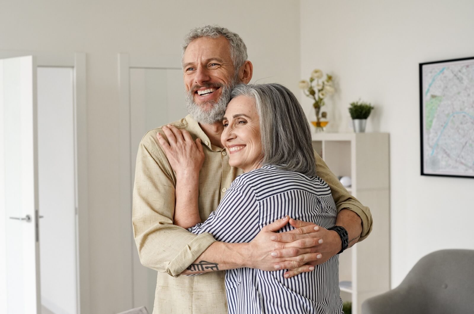 A smiling older couple standing and holding each other in a loving embrace.