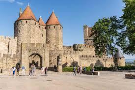 A stone castle with a large stone wall and a large stone wall with Carcassonne in the background

Description automatically generated with medium confidence