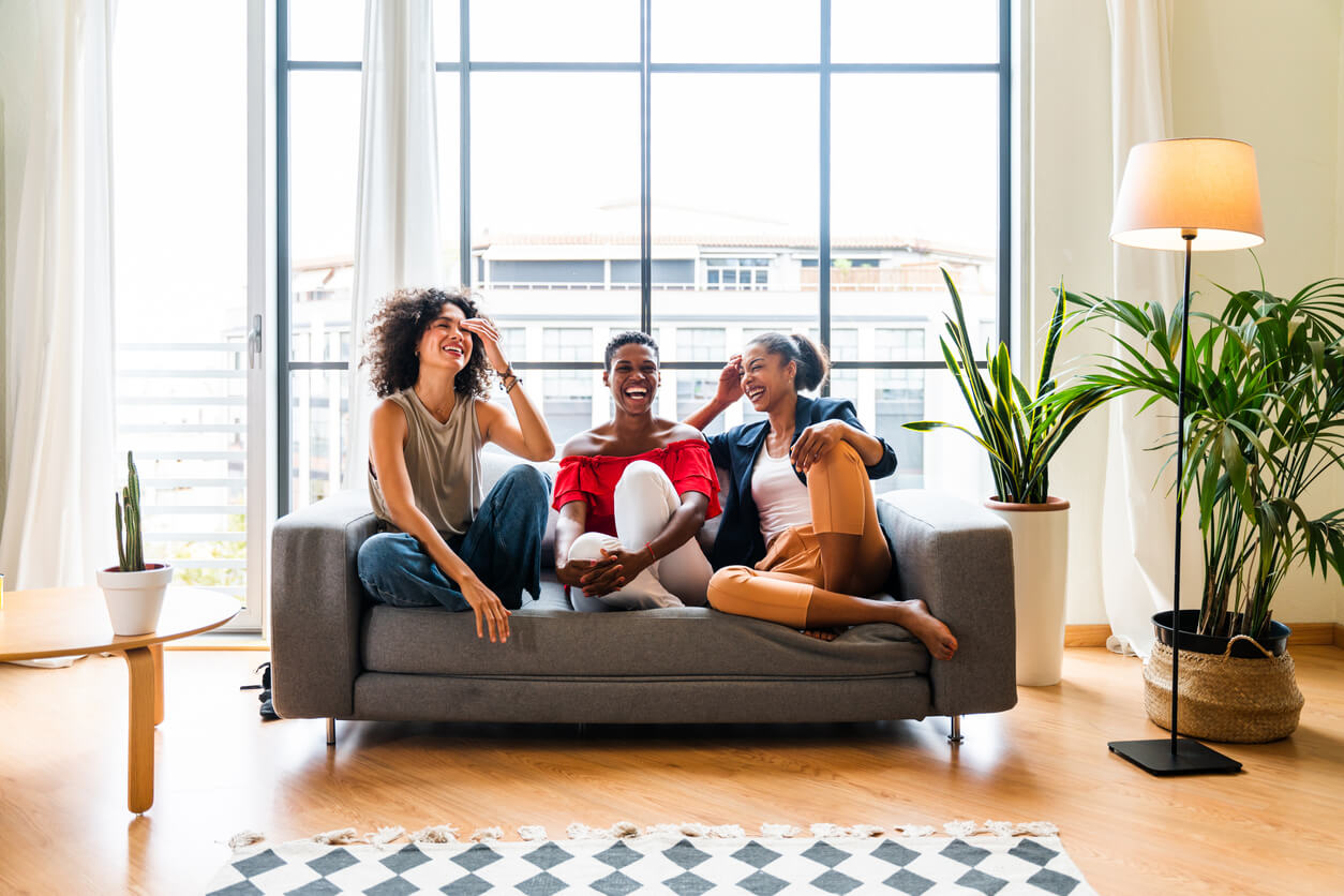 Trois jeunes étudiantes assises sur le canapé de leur logement étudiant en France. Elles sont très joyeuses, mettant en avant l'ambiance conviviale de la colocation