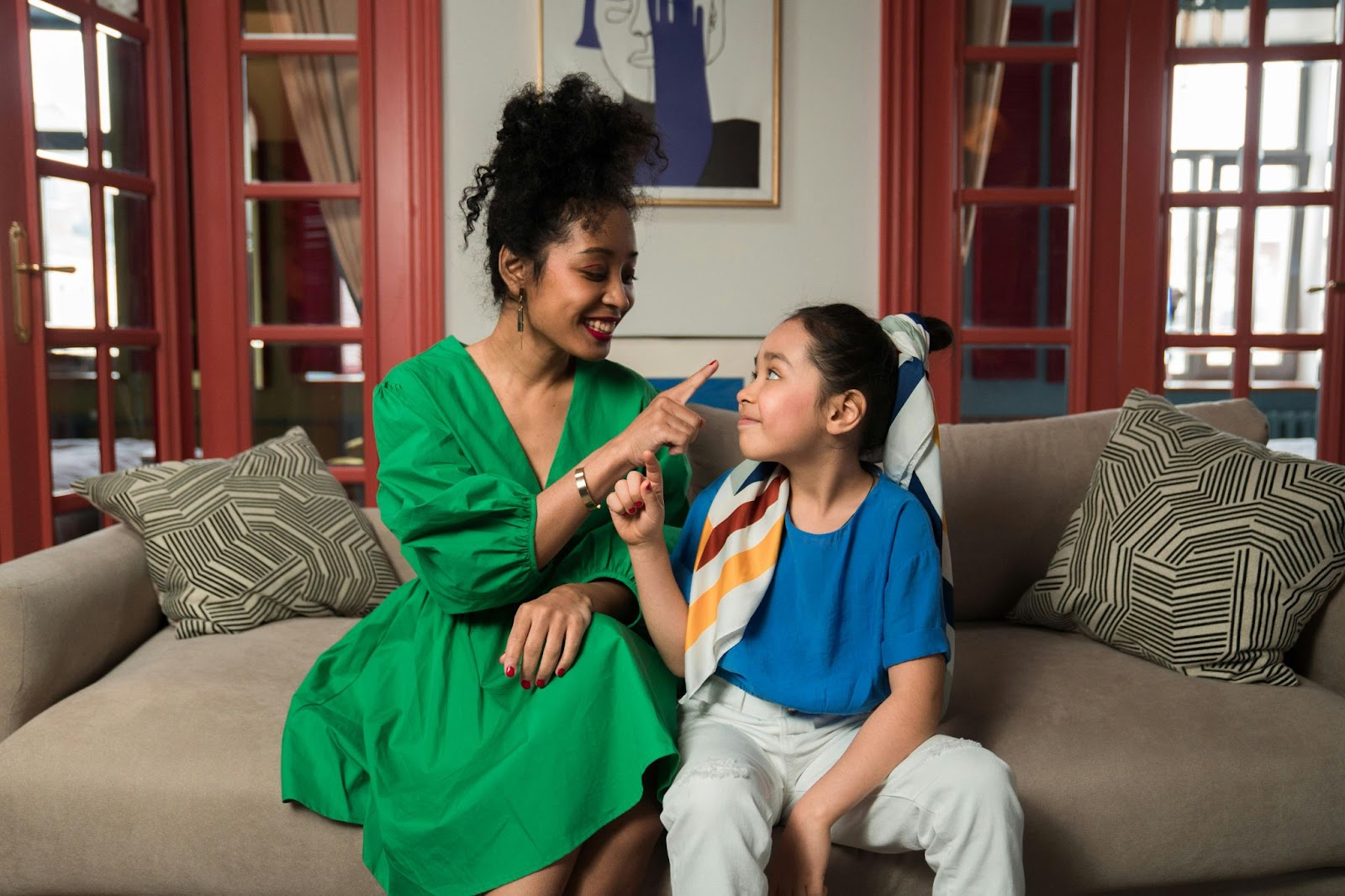 A mother having a conversatin with her young daughter on the couch