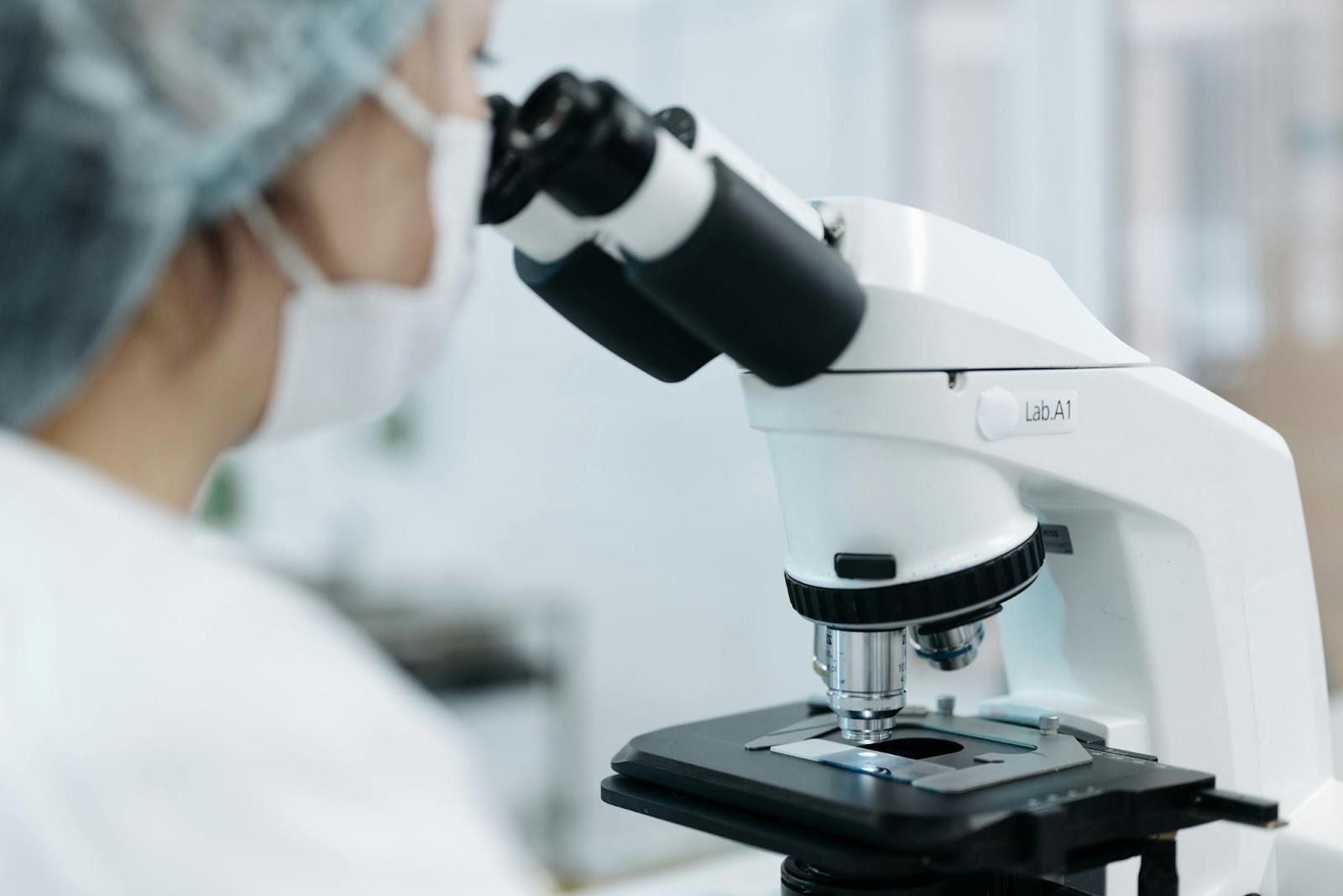 A person looking through a microscopeAI-generated content may be incorrect.