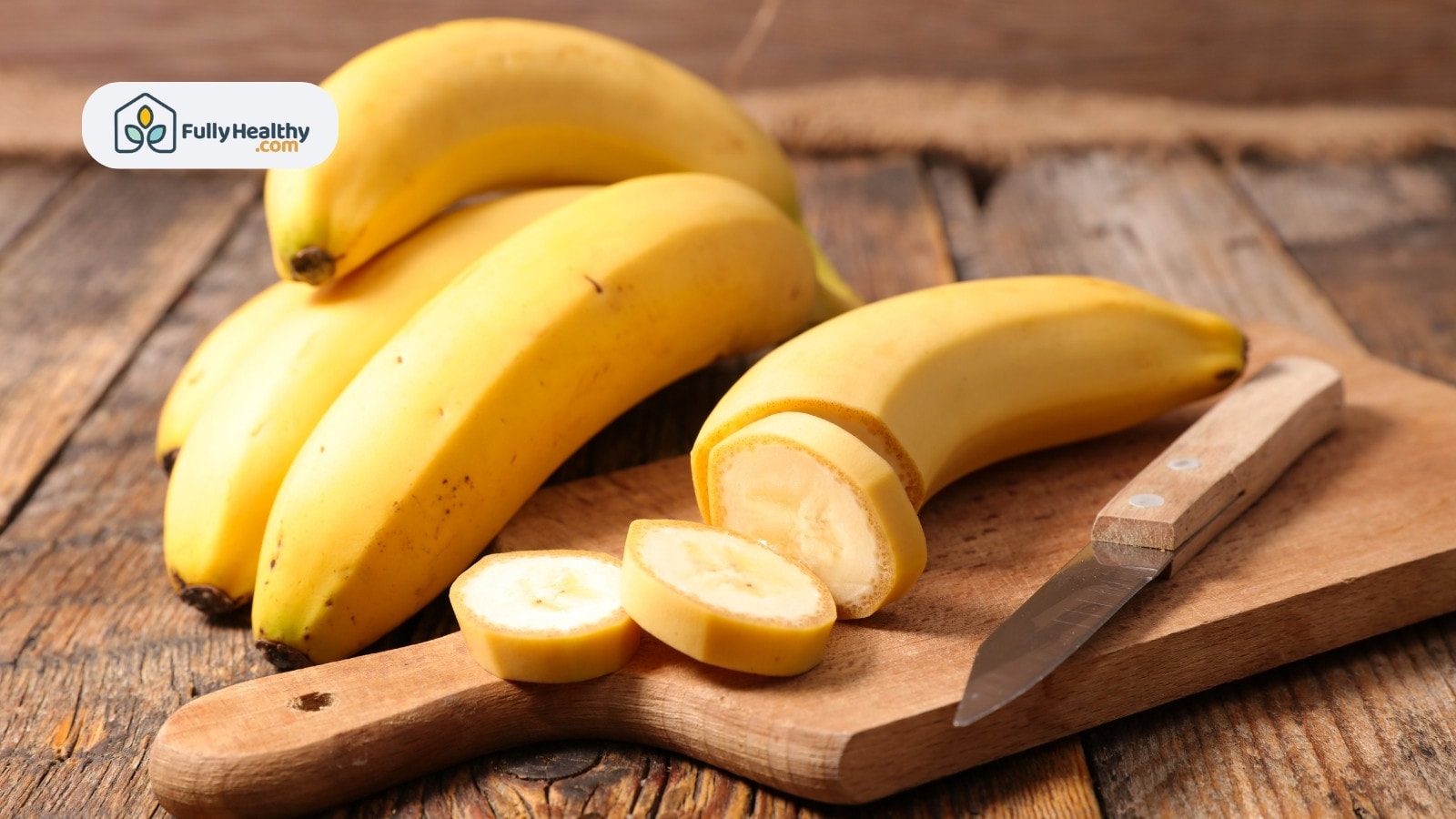 Sliced banana on cutting board with whole bananas behind