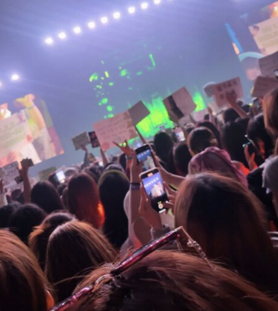 A picture of fans holding sketchbook in a concert