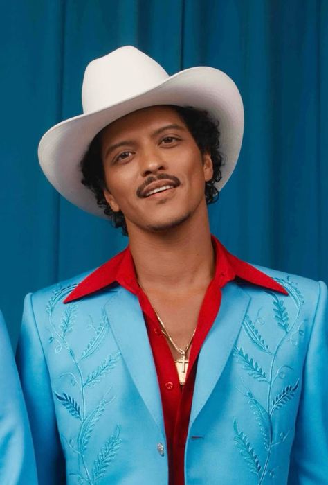 This contains an image of Bruno Mars   in a blue suit and red shirt with a white hat on his head