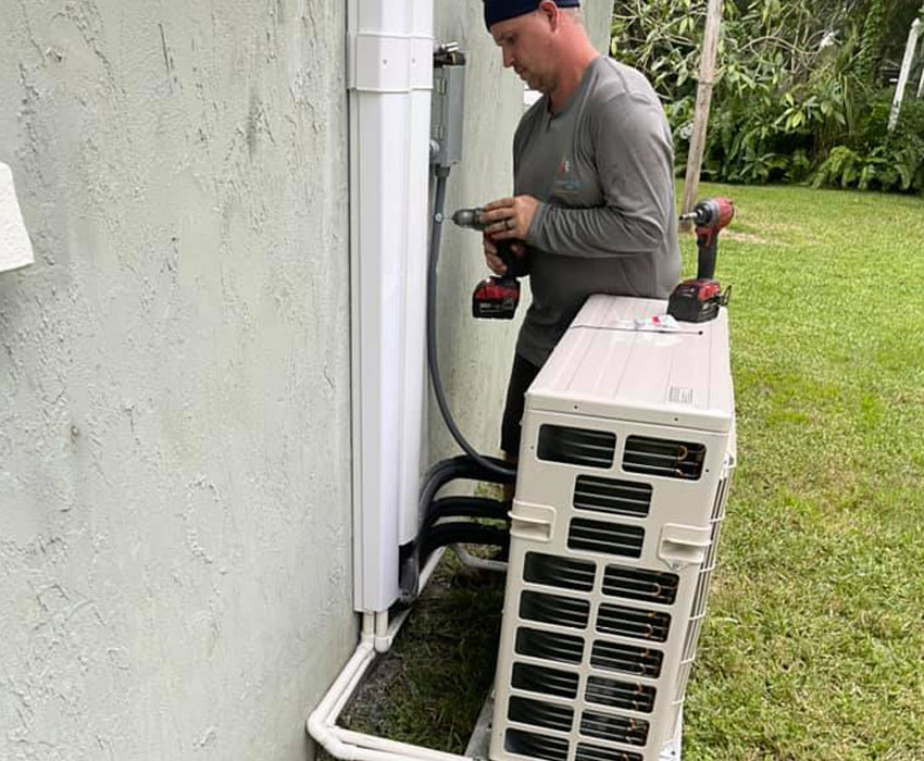 A Streamline Heating and Air HVAC motor blower replacement technician working outdoors with a drill