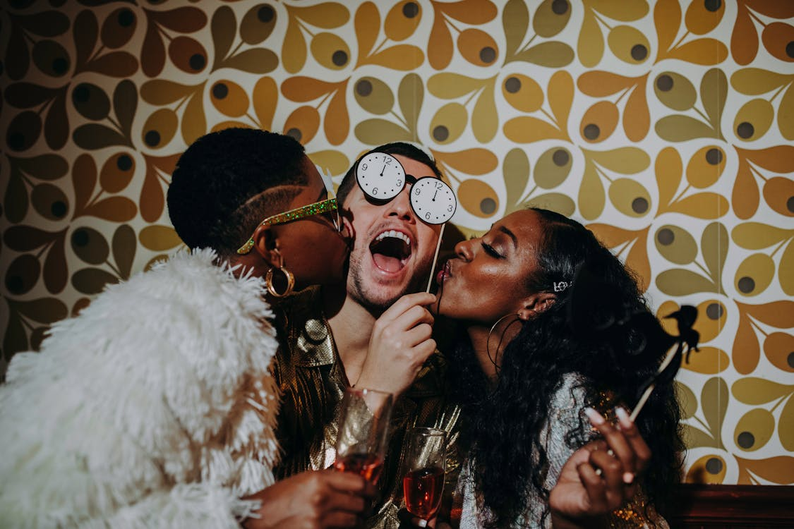 Photo by RDNE Stock project: https://www.pexels.com/photo/women-kissing-a-man-at-the-party-6224720/ 