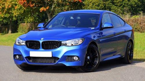 Free Modern blue luxury car parked by a scenic roadside on a sunny day. Stylish design. Stock Photo