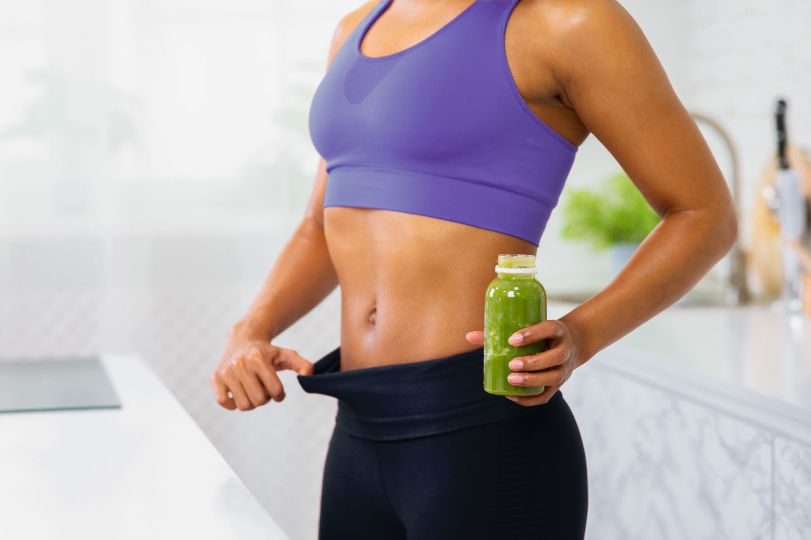 Woman showing loose pants after healthy weight loss with metabolic reset