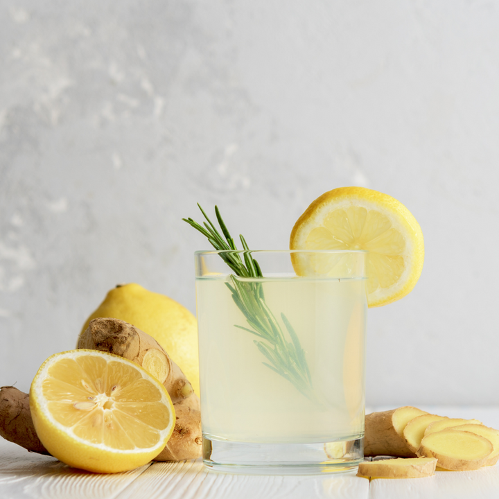 ginger water on table with some lemon slices and ginger root next to it