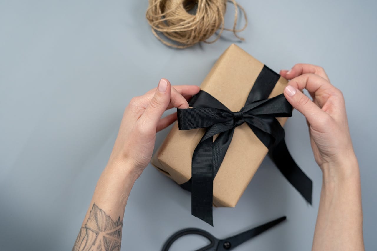 Hands wrapping a gift box with black ribbon, an idea for feathered friends and coffee-loving dads